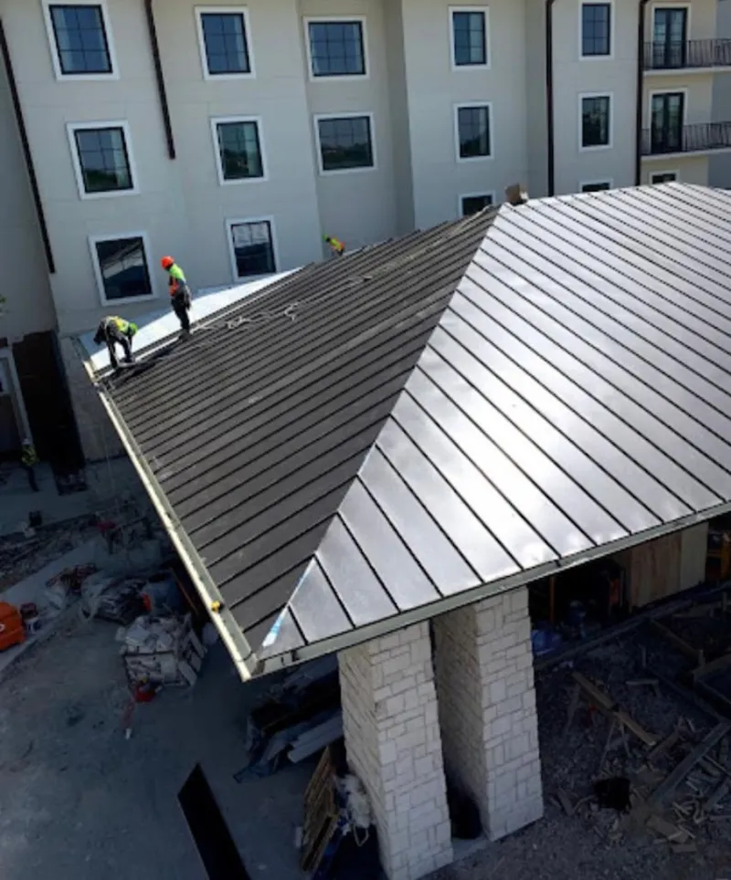 Crew installing standing seam metal roof panels on a commercial project in Jackson